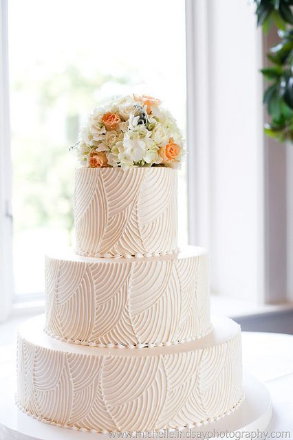 a three tiered wedding cake with flowers on top