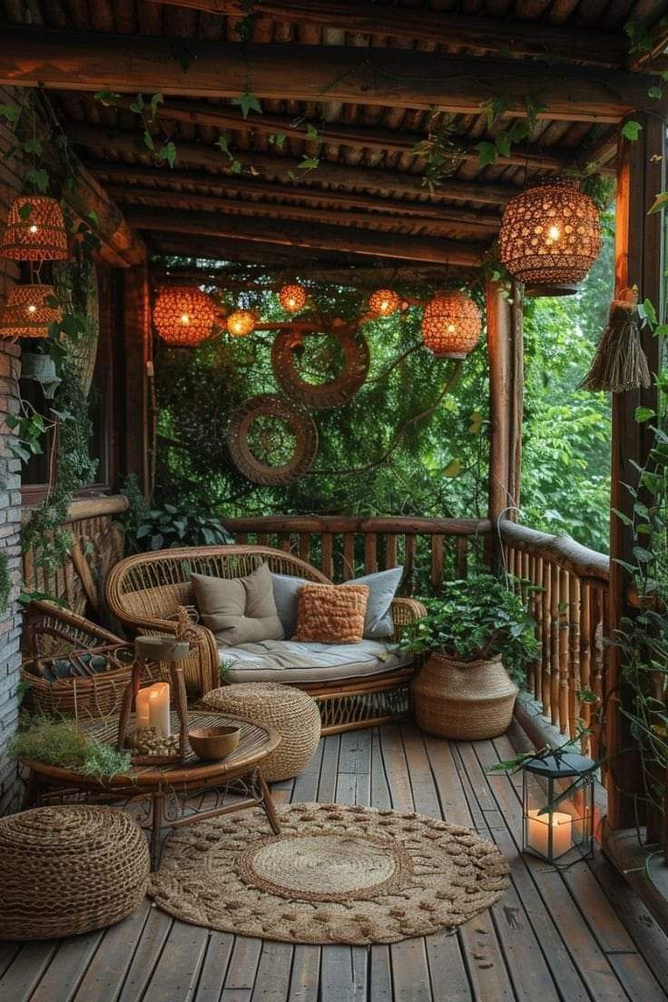 an outdoor porch with wicker furniture and plants on the deck, surrounded by greenery