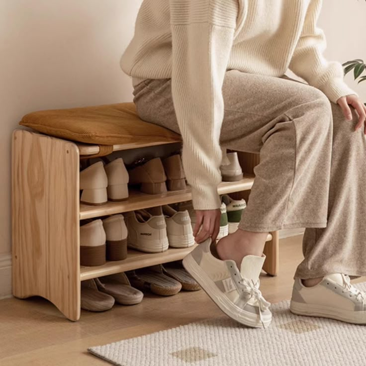 a woman is sitting on a wooden shoe rack