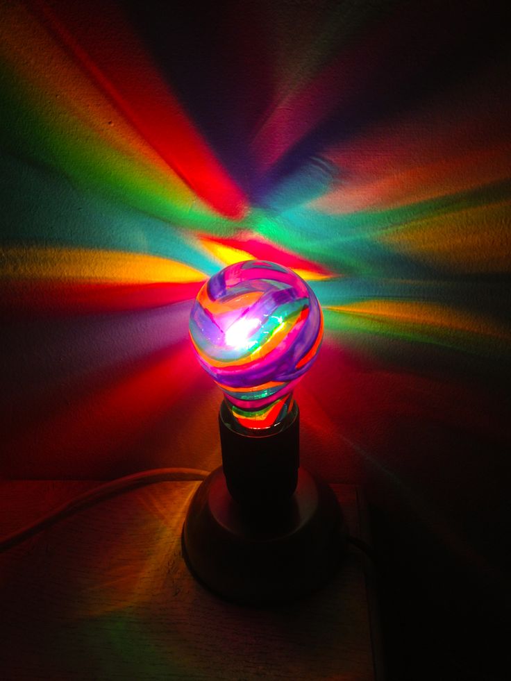 a multicolored light is shining brightly on a dark surface with its reflection in the lens