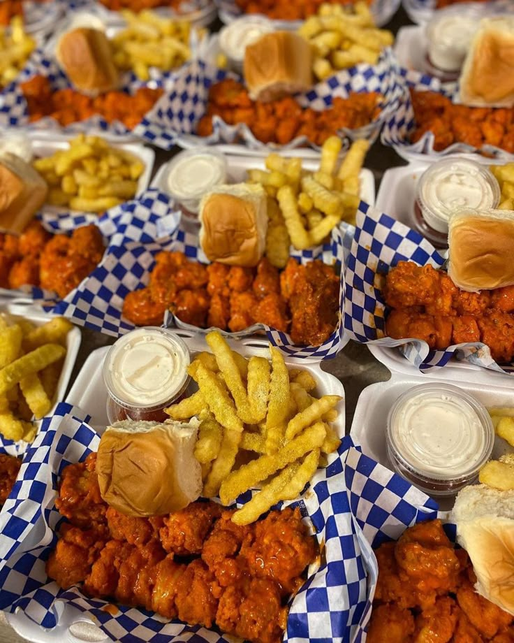 several trays filled with different types of food on top of checkered table cloth