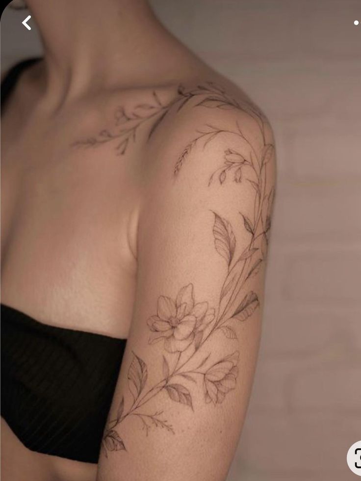 a woman's arm with flowers and leaves tattooed on the back of her shoulder