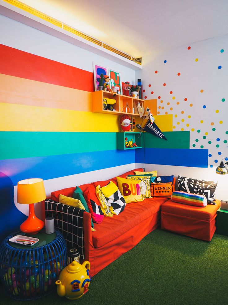 a brightly colored living room with lots of furniture and decor on the walls, including a rainbow painted wall