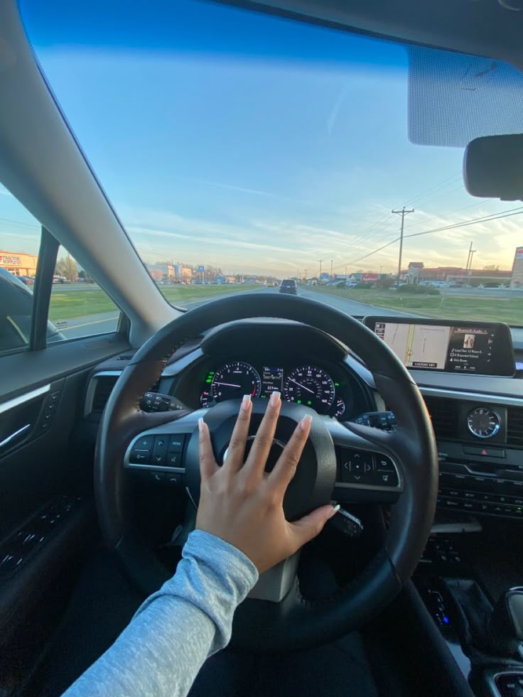 a person driving a car with their hand on the steering wheel and hands on the dashboard