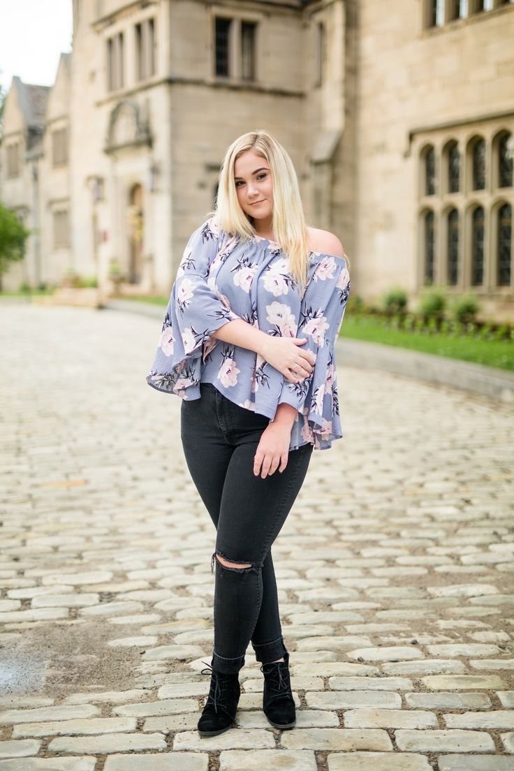 a woman standing in front of an old building wearing black jeans and a blue top