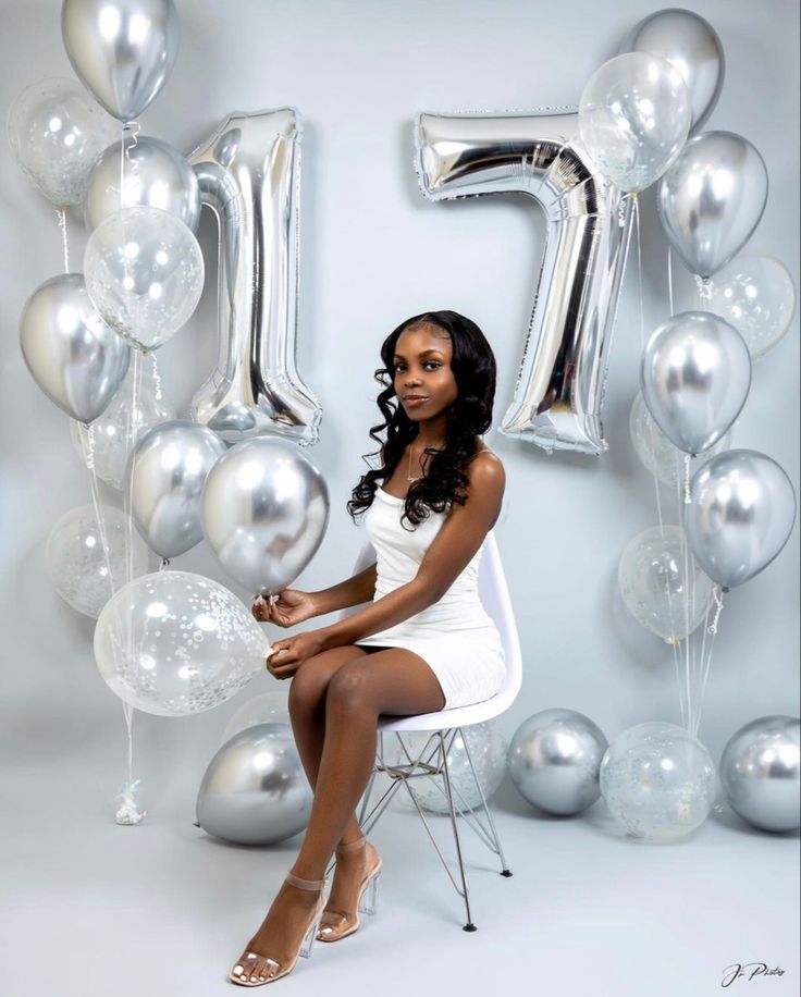 a woman sitting on a chair in front of balloons and the number fifty five sign