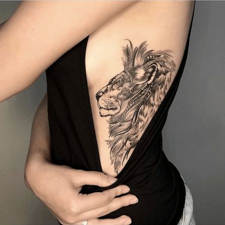 a woman with a lion tattoo on her back is holding her lower back and the upper half of her body