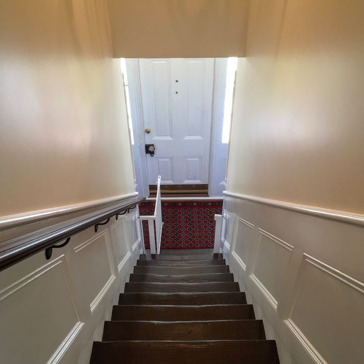 the stairs lead up to an open door in a house with carpeted flooring