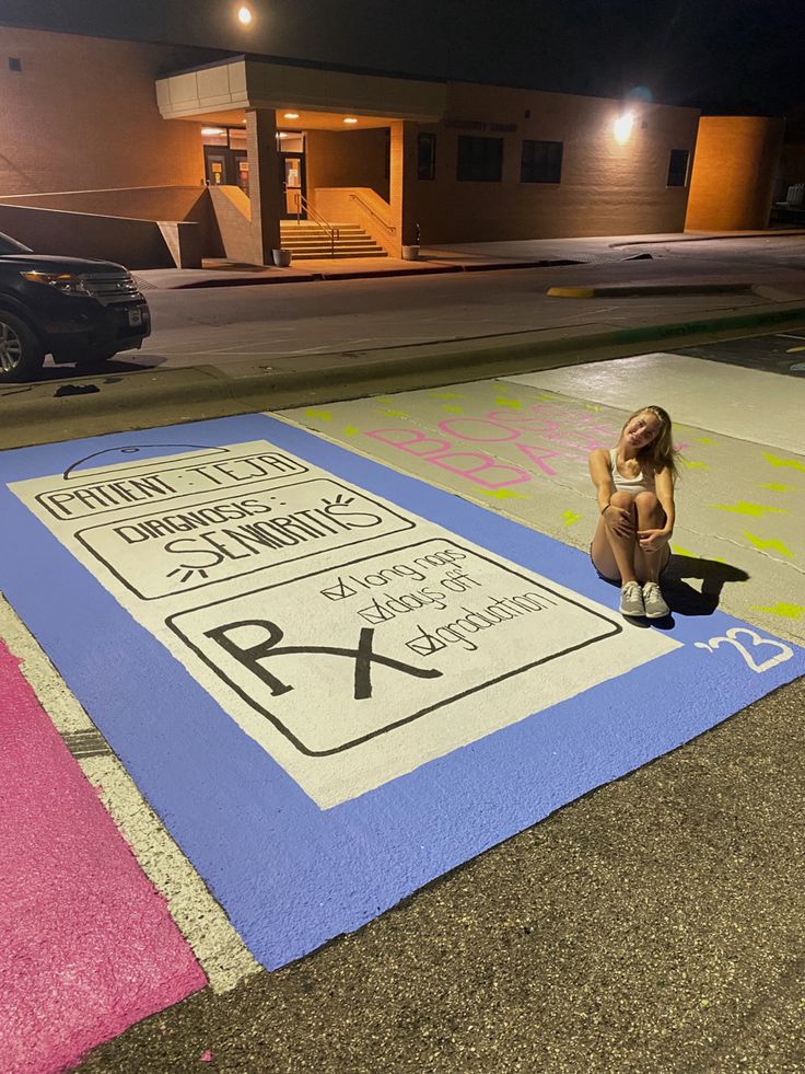 a woman is sitting on the ground in front of a parking lot with no parking signs