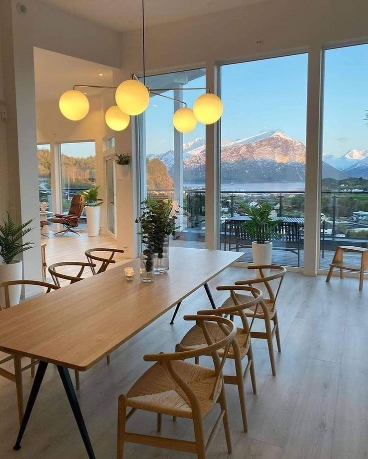 a dining room table and chairs in front of large windows