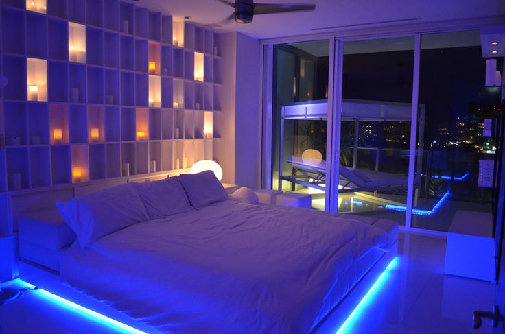 a bedroom with blue lights on the walls and a large bed in front of a window