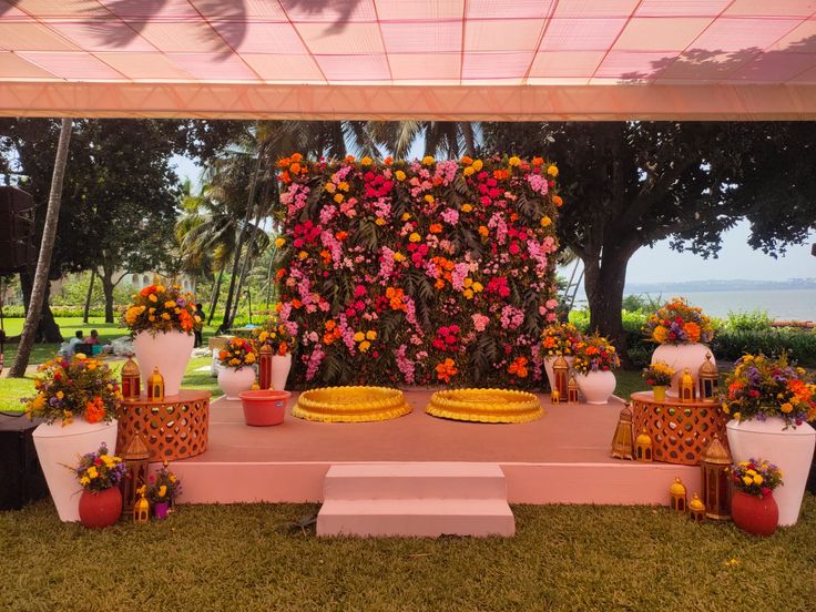 an outdoor wedding setup with flowers on the wall and plates in front of each other