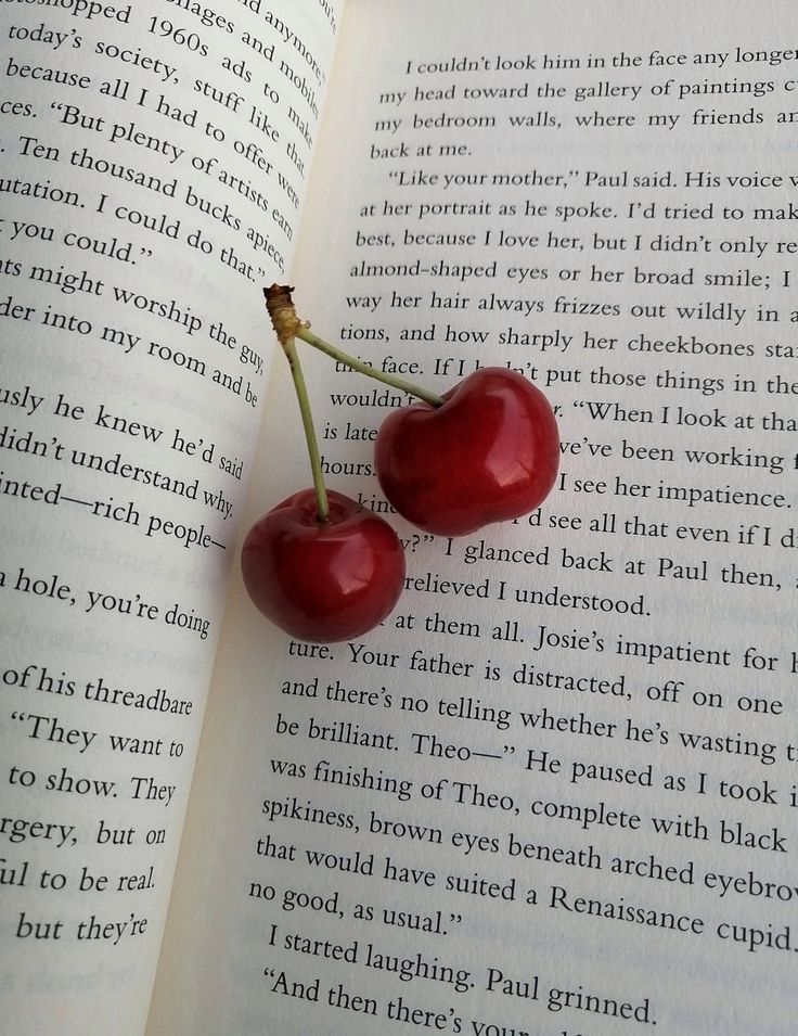 two cherries are sitting on top of an open book, with the pages in english