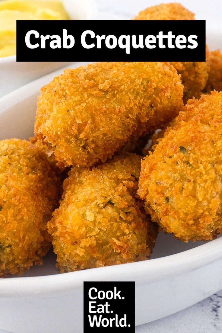 crab croquettes in a white bowl with lemon wedges on the side