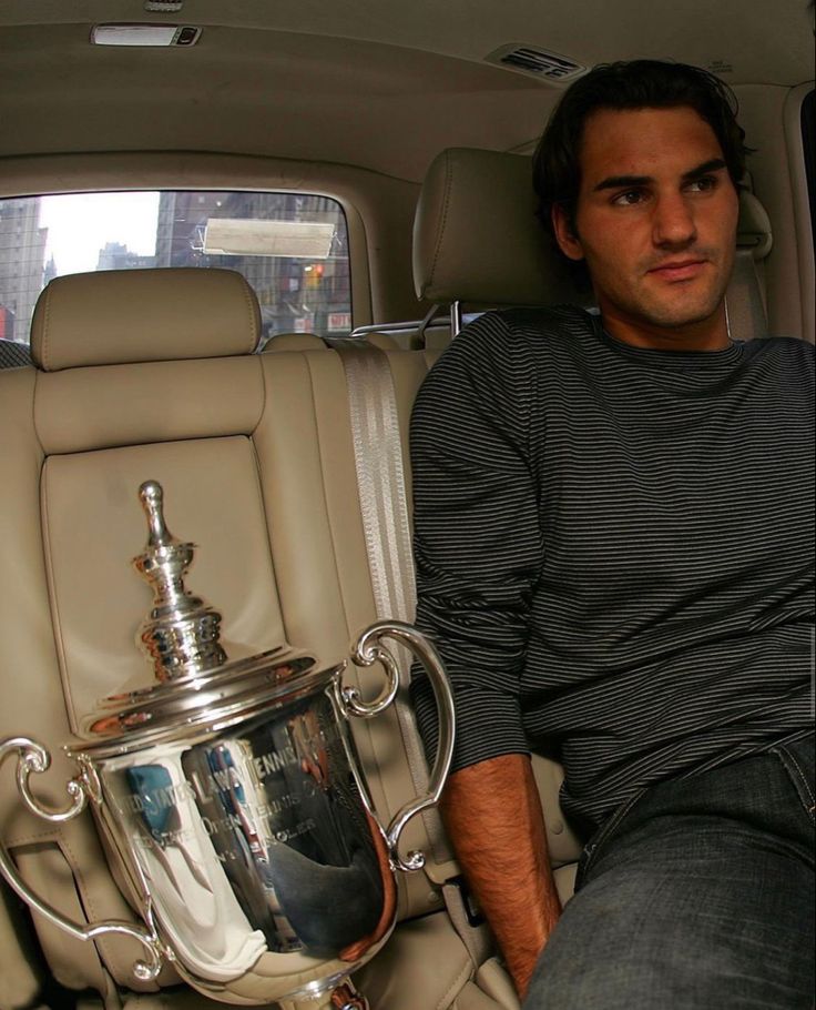 a man sitting in the back seat of a car next to a trophy