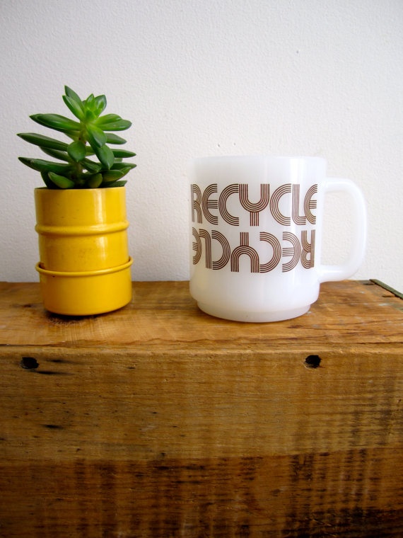 a small potted plant sitting next to a coffee mug on top of a wooden table