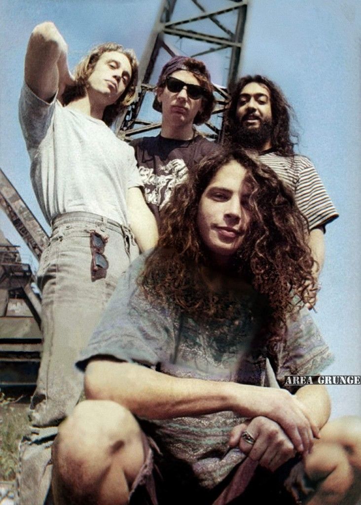 a group of men standing next to each other on top of a metal bridge over water