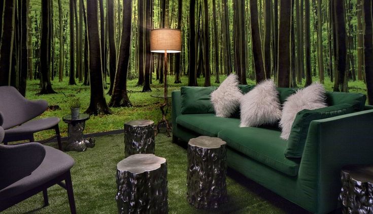 a green couch sitting in front of a forest filled with lots of tree stumps