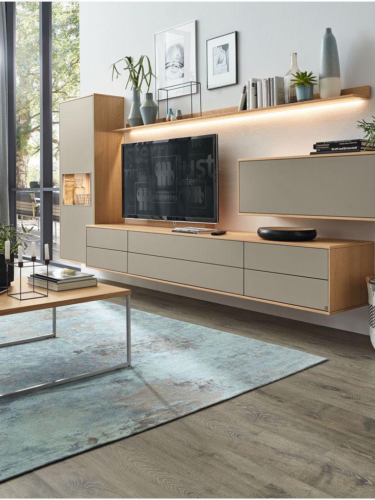 a living room with a large tv on top of a wooden entertainment center next to a window