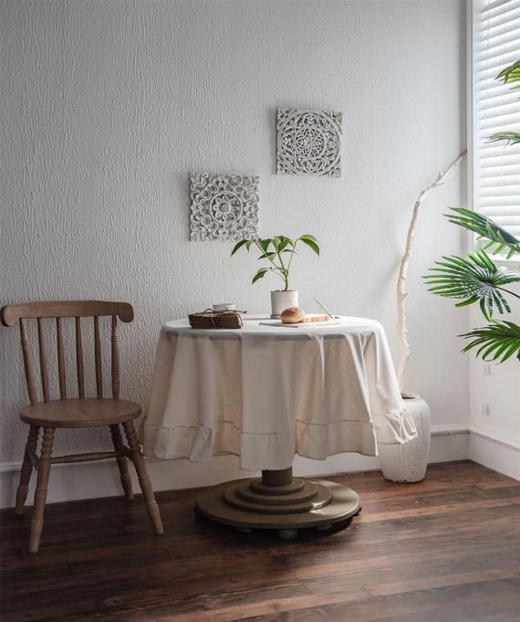 a table with a white cloth on it next to a chair and potted plant