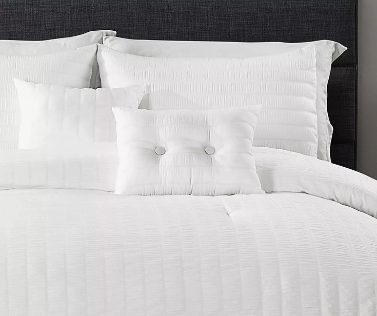 a bed with white sheets and pillows on it