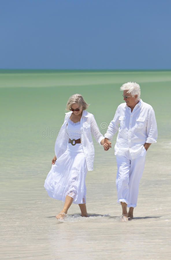 an older couple walking on the beach holding hands royalty photo, image and stock photography