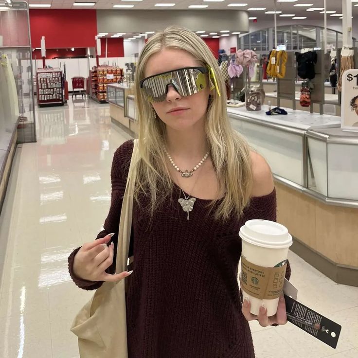 a woman wearing sunglasses and holding a coffee cup