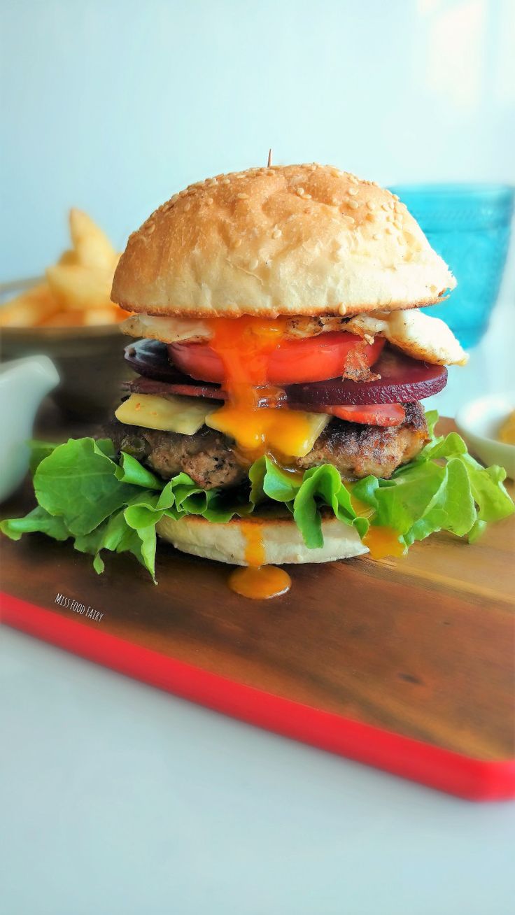 a cheeseburger with lettuce and tomato on a cutting board