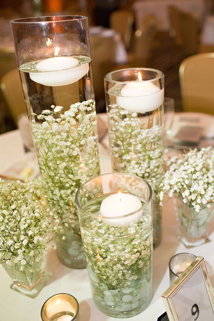 three vases with flowers and candles on a table