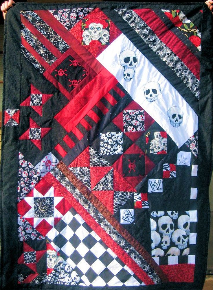 a person holding up a quilt with skulls on it