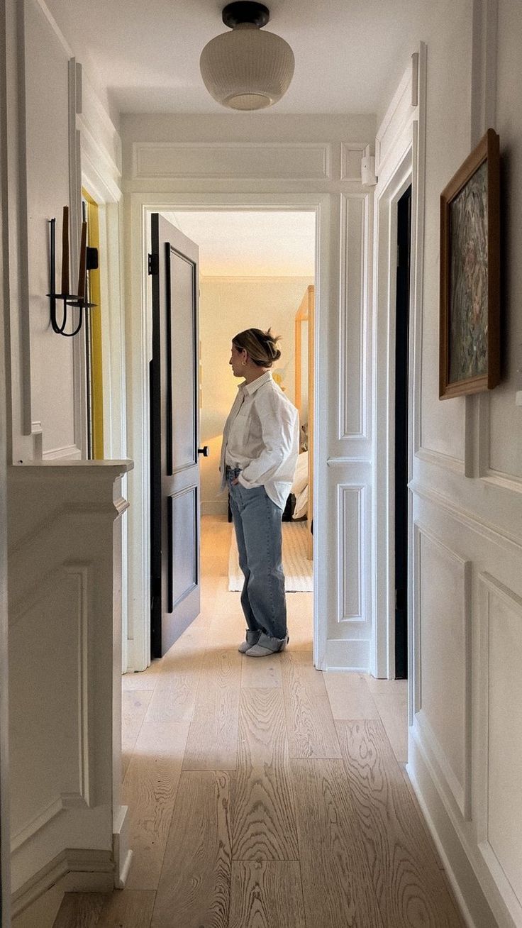 a woman is standing in the hallway with her hand on her hip and looking at herself