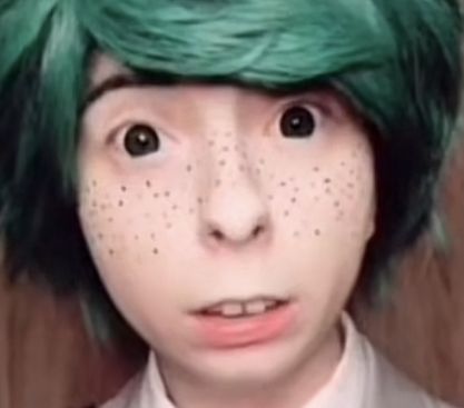 a person with green hair and freckles on their face