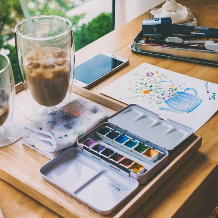 a wooden table topped with lots of art supplies