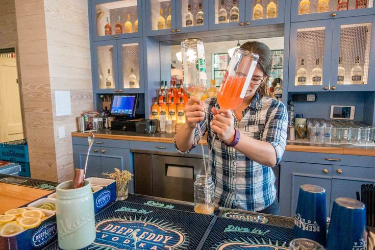 a man holding up a drink in front of a bar