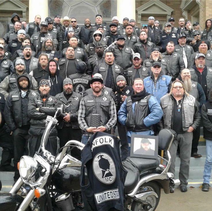 a group of people standing around a motorcycle in front of a building with police officers on it