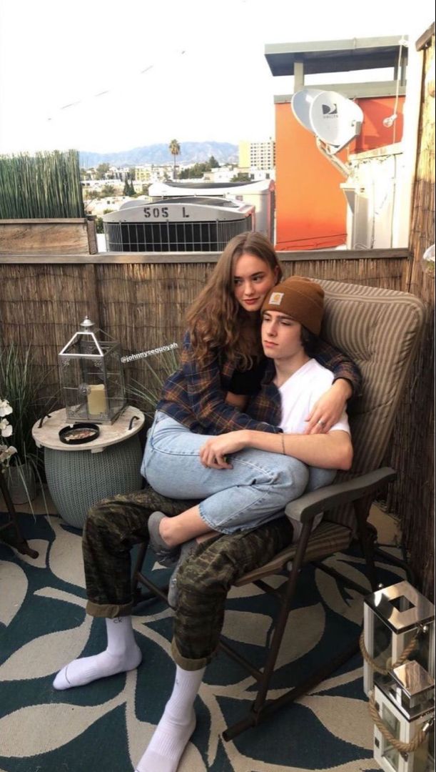 two people are sitting on a chair with their arms around each other