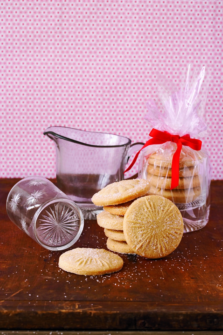 some cookies are sitting on a table next to a glass bowl and measuring cup with a red ribbon