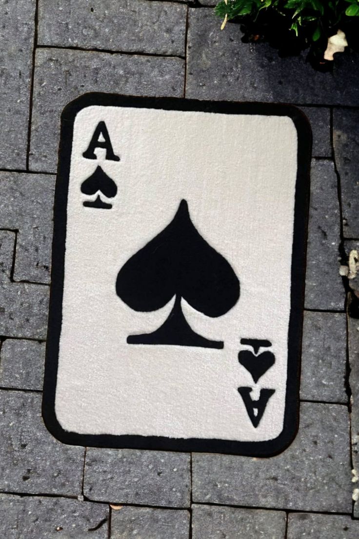 a black and white playing card rug sitting on top of a brick floor next to a potted plant