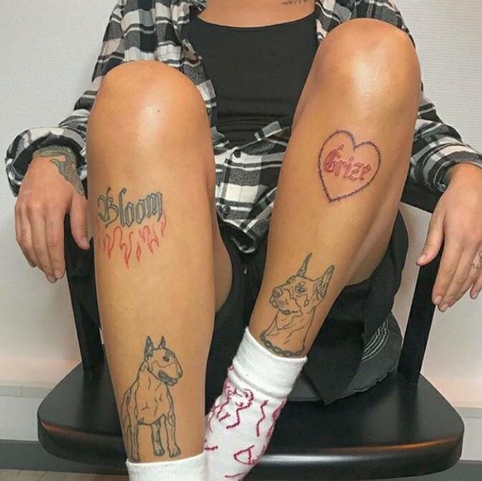 a woman sitting on top of a chair with two tattoos on her legs and leg