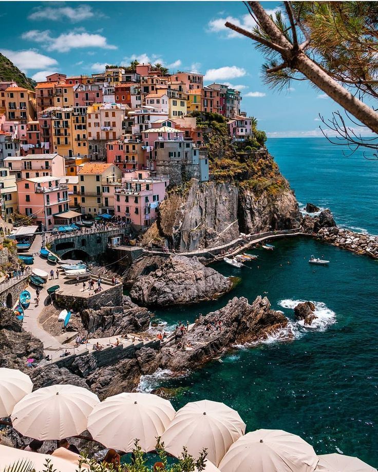 the beach is lined with umbrellas and houses on top of cliffs overlooking the ocean