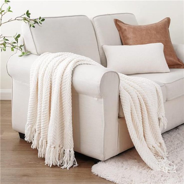 a white couch sitting on top of a hard wood floor next to a plant in a living room