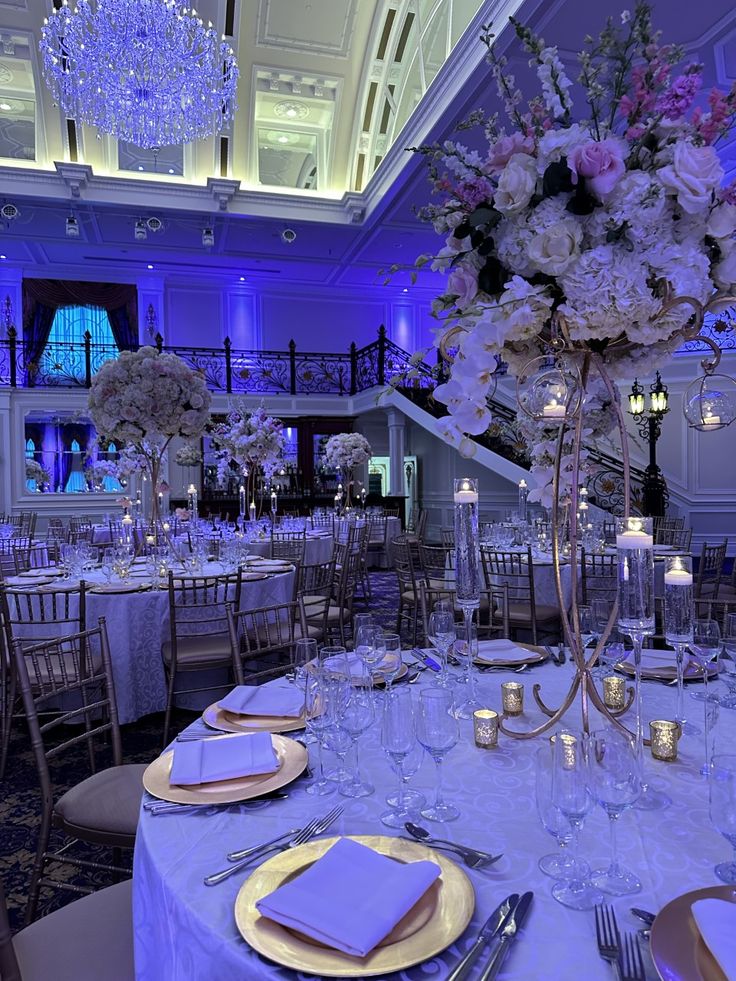 a table set up for a formal dinner with flowers and candles on it in a ballroom