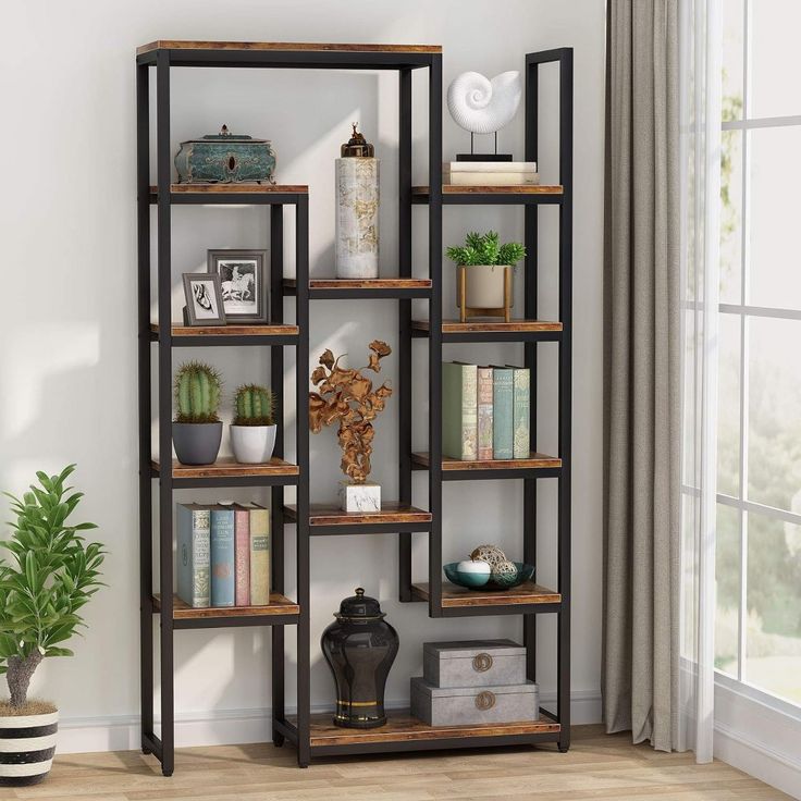 an open bookcase with many books on top of it in a living room next to a potted plant