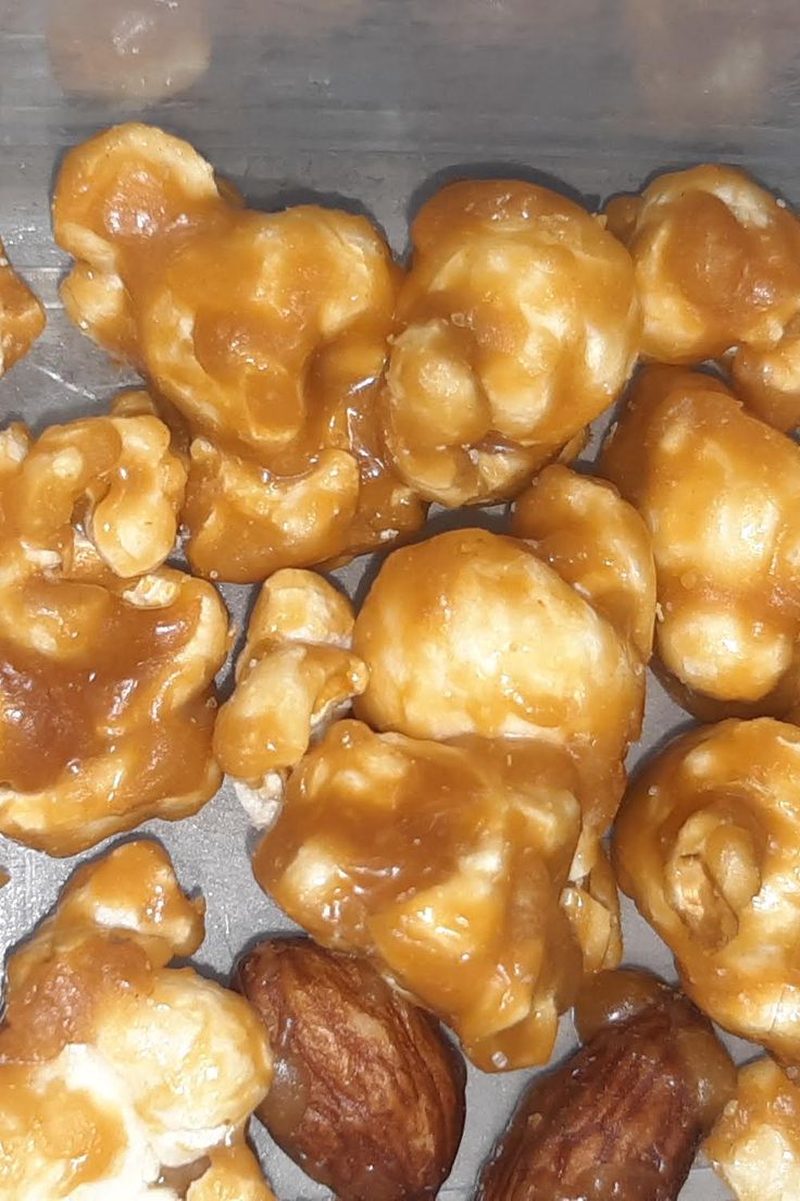 some nuts are sitting on top of tin foil and have been coated with caramel