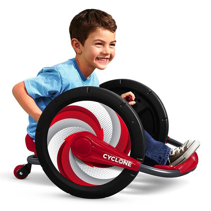 a young boy is riding on a toy car with wheels and steering wheel, while smiling at the camera