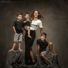 a woman poses with two boys and an infant on top of a pile of cloth