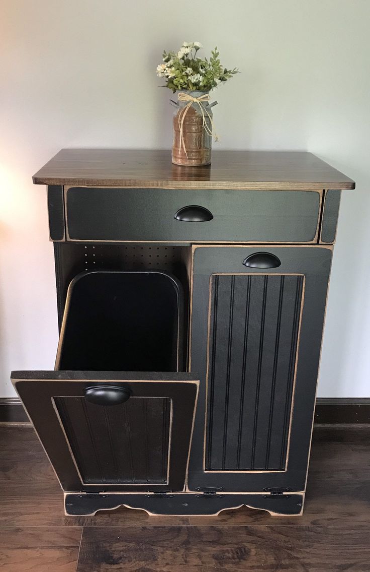 a black and gold cabinet with two trash cans