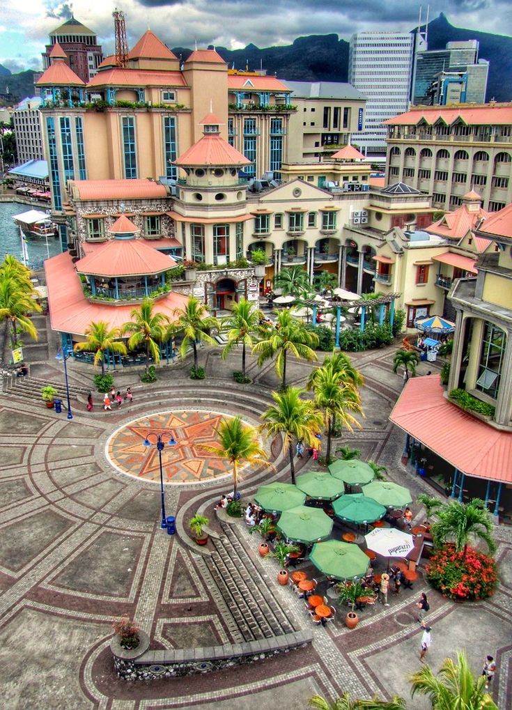 an aerial view of a city with many buildings and umbrellas in the center, surrounded by palm trees