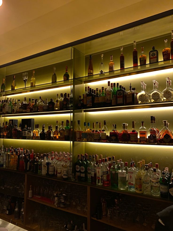 the bar is filled with many different types of liquor bottles and glasses on it's shelves