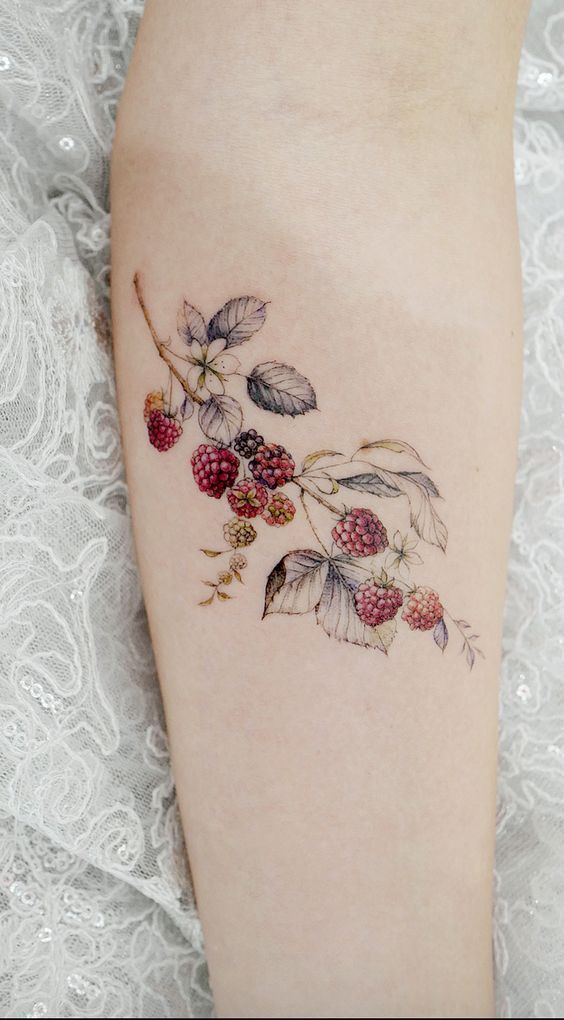 a close up of a person with a tattoo on her leg and berries growing out of it